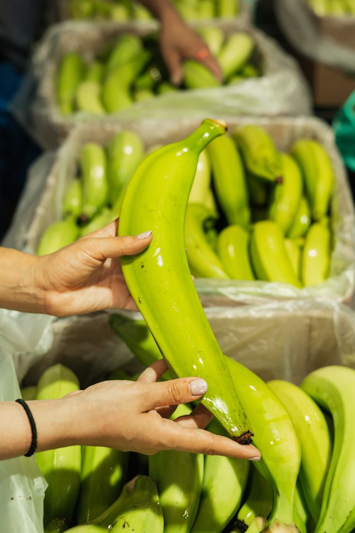 Selecting a green plantain over packed boxes